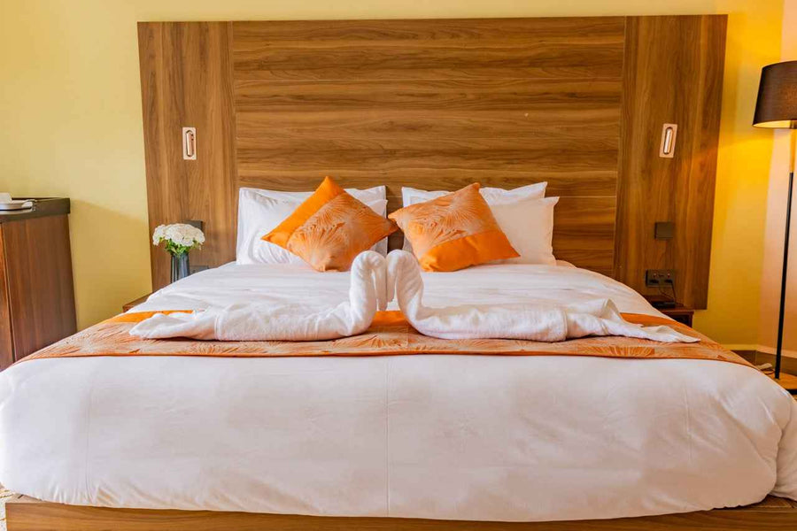 King bed with orange cushions and balcony door at Karen Plains Hotel, a couples' room in Karen, Nairobi