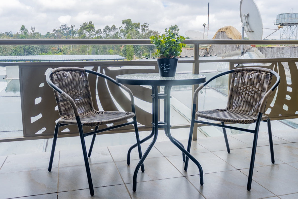 Balcony table and chairs with green trees beyond at Karen Plains Hotel, ideal for a weekend in Karen, Nairobi